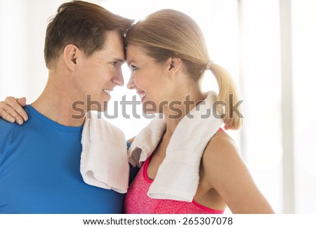 Happy loving mature couple in sports clothing looking at each other at home