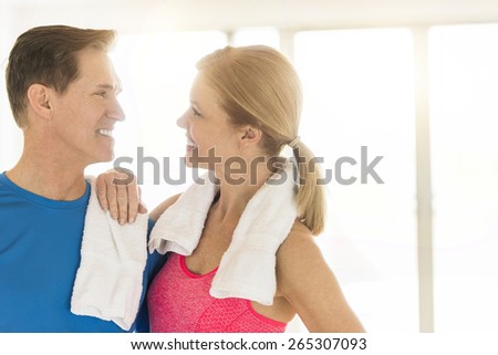 Happy mature couple in sports clothing looking at each other at home