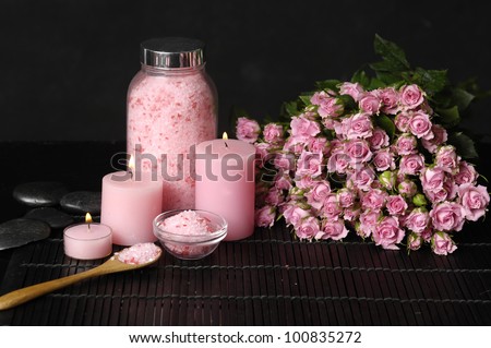 Spa setting with candle and branch rose on towel and soap, salt in bowl