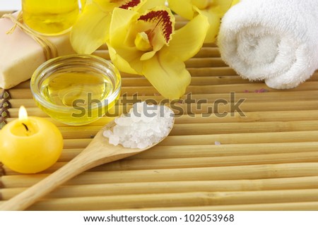 Spa products with orchid flowers and candle, soap, towel with salt in spoon
