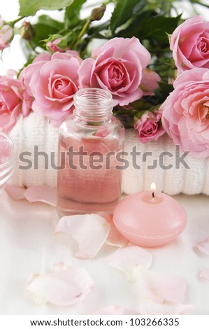 Spa setting with branch roses on towel and candle, salt in bowl, massage oil