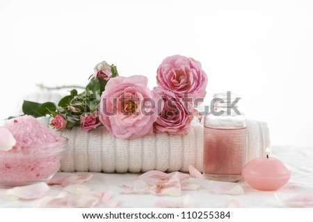 branch rose on towel with salt in bowl and candle, massage oil on white towel
