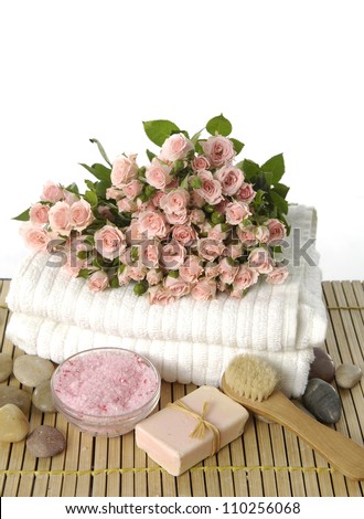 Bouquet of roses on towel with soap and salt in bowl on mat background