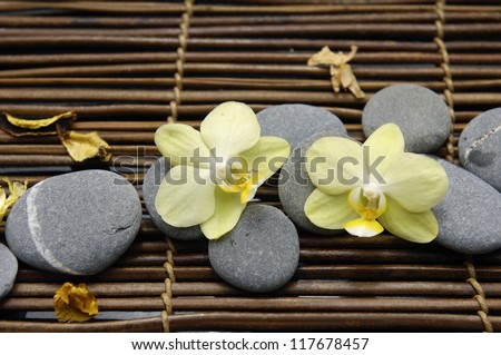 Pile stones with yellow two orchid on bamboo stick straw mat