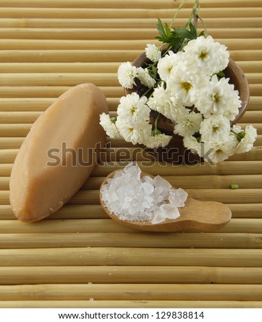 Branch White flower in bowl and salt in wooden spoon on bamboo mat