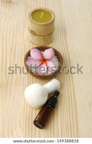 Salt with frangipani on bowl ,candle, massage ball on a wooden board