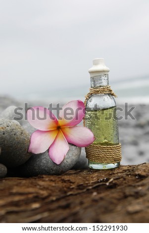 massage oil , frangipani flower ,stones, on old wood -beach in sunset time