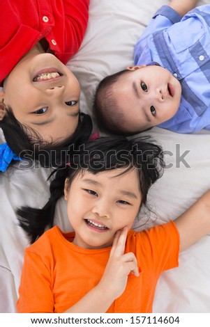 Three happy kids ,baby on the floor laying on