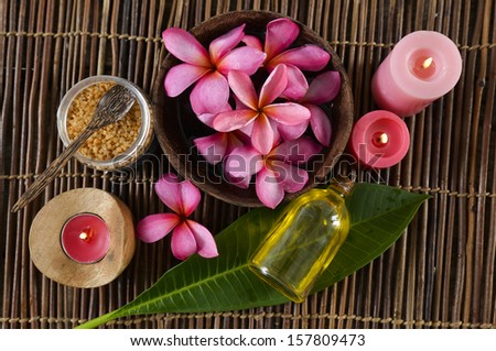 Many red frangipani in bowl ,red candle ,leaf ,salt in bowl on bamboo mat