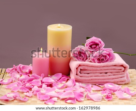 spa sitting with candle and rose flowers on towel with petals