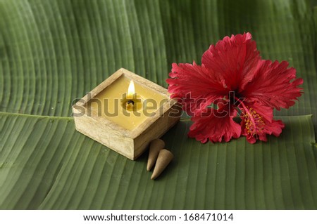 Red hibiscus with handmade candle on green banana leaf