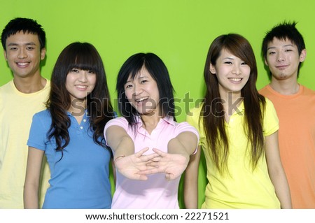 Five happy young friends wearing colorful t-shirt on green background