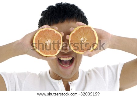 Young man with tropical fruit halves over eyes smiling