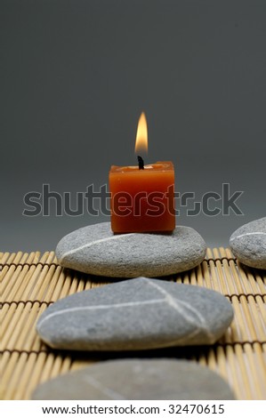 A light candle and row of stones on mat