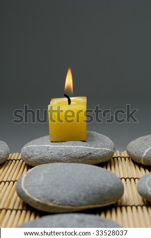 alight candles and zen stone on mat