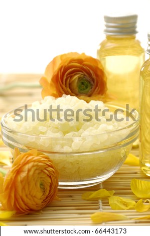 spa essentials- ranunculus flowers on bowl of salt and massage lotion,