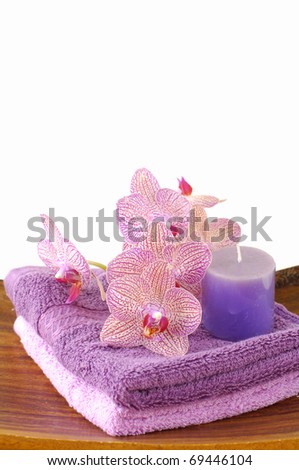 Pink orchid and towel and candle in wooden bowl of on stick straw mat