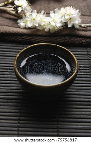 Spa Concept- cherry blossom flowers on towel with bowl of water on mat