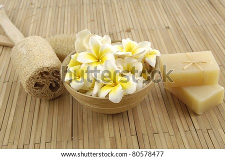 frangipani flower in bowl with natural handmade soap on bamboo mat