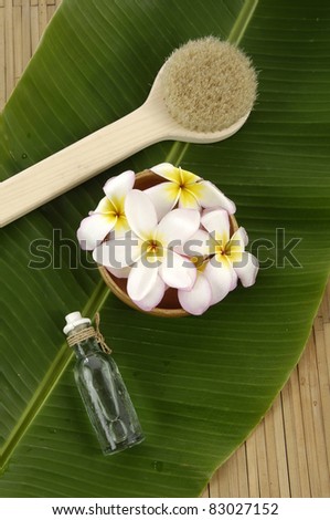 Sea salt bath in spoon with frangipani flower in bowl on banana leaf