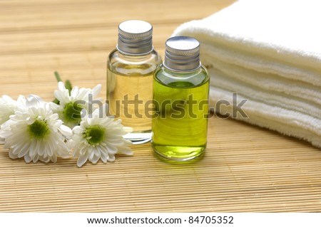 bottles with massage oils and towel with flower on bamboo stick straw mat