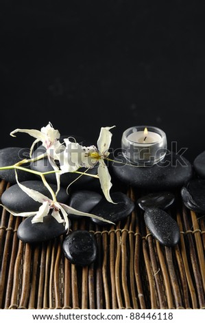 Tropical orchid and candle with zen stones on bamboo mat