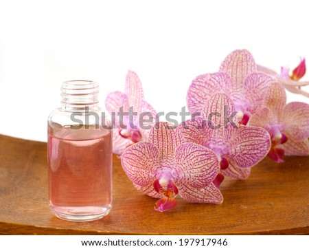 Pink orchid and massage oil on wooden bowl