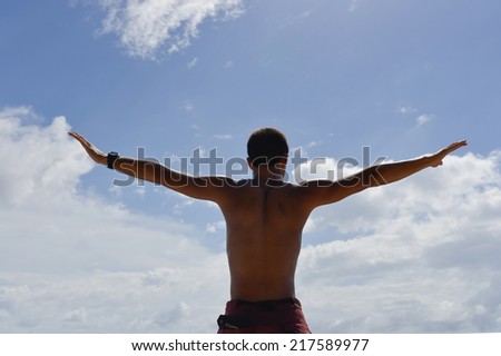 Young man stretching arms up towards the sky