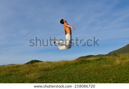 Man jumping against sea and mountain with blue sky