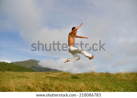 flying jumping man on a green meadow with a beautiful cloudy sky