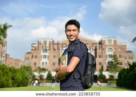 Stock image of university student holding book at college