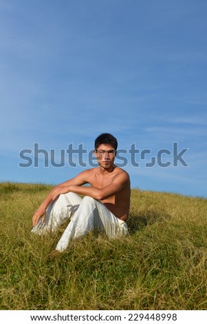 sport model. -Yong muscular man sitting on mountain grass