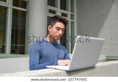 Young male college student use laptop at campus