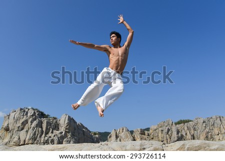 male model with muscles in exercise jumping outdoors