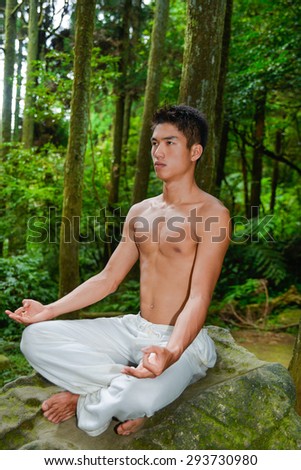 Healthy muscular young man sitting doing yoga over forest,