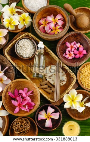 wooden bowl of color sea salt with ,candle ,massage oil and frangipani on banana leaf