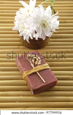 natural handmade soap and flower in wooden bowl on bamboo mat
