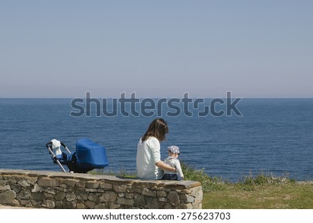 Mom and son sitting in the coast, with the baby stroller