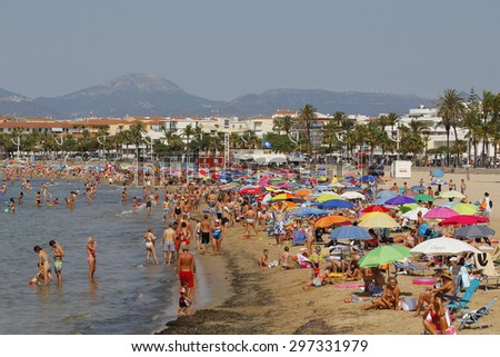 CAMBRILS, SPAIN - JULY 12, 2015: People having fun on the beach in a hot sunny day on July 12, 2015 at the beach of Cambrils in Catalonia, Spain, a famous summer destination