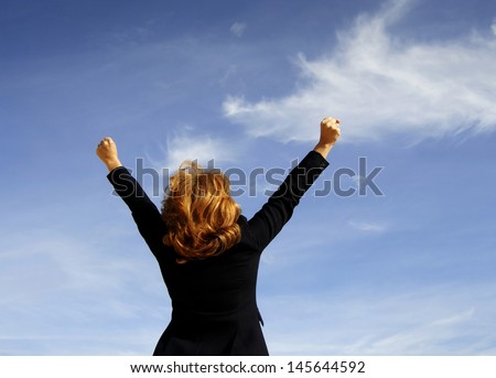 Successful business woman with arms up and blue sky background