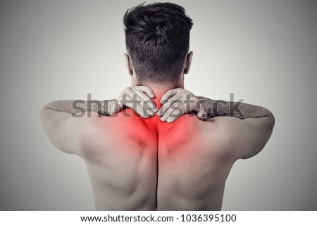 Black and white shot of man from back having red spot of pain and trauma in neck.
