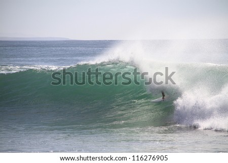 Surfer tube riding a wave in Supertubos, Peniche, Portugal