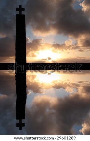 Cross silhouette at sunset time under cloudy sky