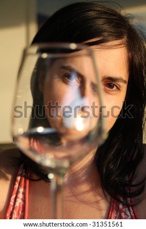 Girl peaking through a empty glass of wine over dinner