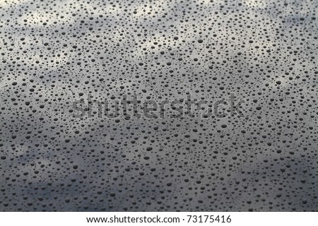 Drops of water on metal with sky reflection