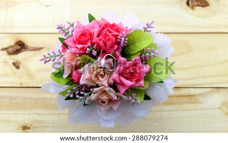 A ring in beautiful rose bouquet on wood background