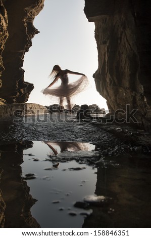 Young attractive woman dancing through hole in rock wall tutu nature see through