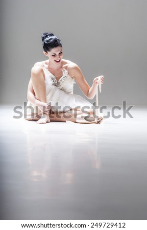 Young beautiful ballerina sitting on floor with ballet shoes