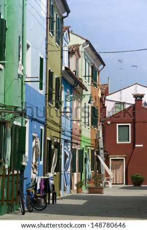 Colorful houses in a street in Burano near Venice with a bike in front of the house on a sunny day with a blue sky