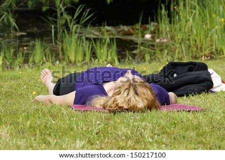 Woman relaxing in the grass during yoga lesson